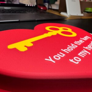 A red heart-shaped 3D-printed decoration with a gold key inset and the text ‘You hold the key to my heart.’ Perfect for a romantic Christmas gift or a creative proposal idea.