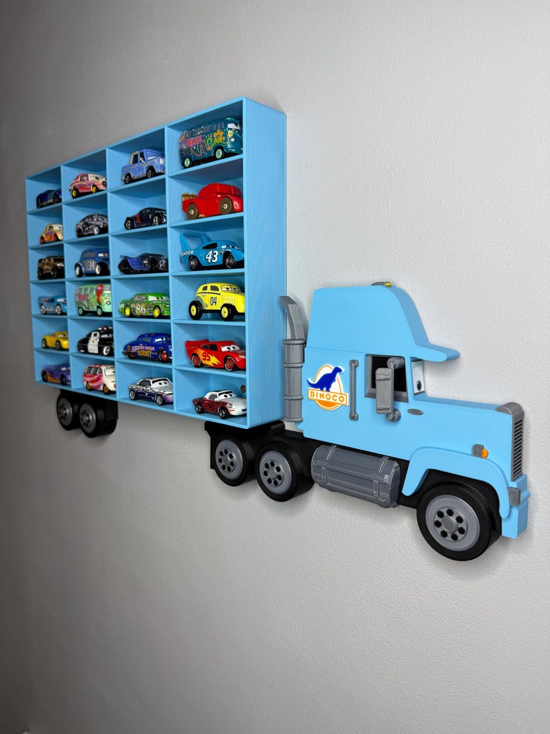May include: A light blue, wall-mounted toy truck with multiple compartments filled with toy cars. The truck features a Dinoco logo and is designed to hold a collection of toy vehicles. The design is a fun and functional storage solution.