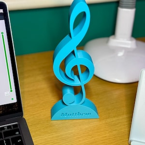 A personalised treble clef ornament in vibrant blue, engraved with “Matthew.” This musical decoration is ideal for music lovers, teachers, and performers, adding a stylish touch to desks, shelves, or studios. A thoughtful custom gift for musicians.