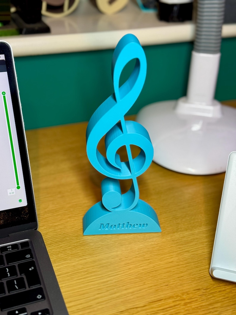 A personalised treble clef ornament in vibrant blue, engraved with “Matthew.” This musical decoration is ideal for music lovers, teachers, and performers, adding a stylish touch to desks, shelves, or studios. A thoughtful custom gift for musicians.