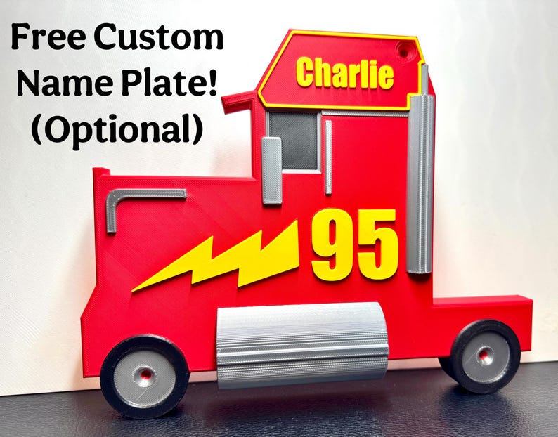 A 3D-printed red truck display inspired by Mack from Cars, featuring a bold yellow “95” and a lightning bolt. Silver details add realism, and a custom nameplate option is glued neatly on, fitting the profile of truck, reading “Charlie.”