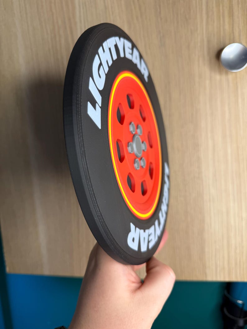 May include: A black and red circular object with the text "LIGHTYEAR" in white. The object has a red center with a silver hub and is reminiscent of a tire.