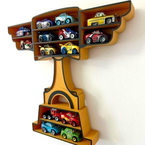 Puede incluir: Estanter&iacute;a de pared amarilla con forma de trofeo, llena de coches de juguete de varios colores. La estanter&iacute;a tiene m&uacute;ltiples compartimentos para exhibir los coches de juguete. Los coches son peque&ntilde;os y detallados, con diferentes dise&ntilde;os y n&uacute;meros.