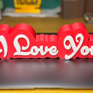 3D printed ‘I Love You’ sign with bold red and white 3D letters. A perfect Valentine’s Day gift, romantic decor, or anniversary present. Unique, high-quality design makes it ideal for bedroom decor, couples’ gifts, or special celebrations of love.