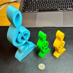 Three treble clef ornaments in blue, green, and yellow, engraved with personalised names. A perfect music-themed decoration for desks, shelves, or studios. Ideal as a musician’s gift, music teacher award, or custom music room decor.