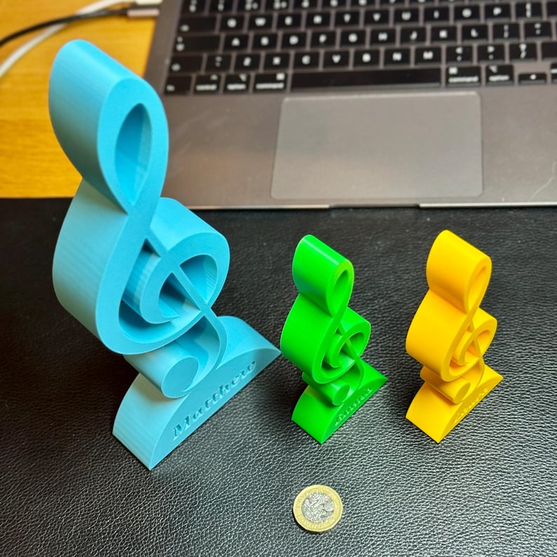 Three treble clef ornaments in blue, green, and yellow, engraved with personalised names. A perfect music-themed decoration for desks, shelves, or studios. Ideal as a musician’s gift, music teacher award, or custom music room decor.