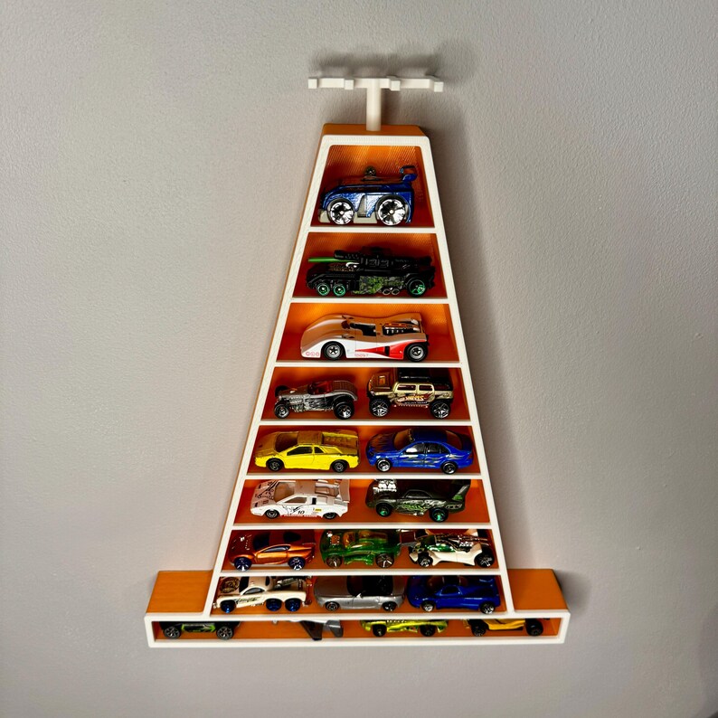 May include: A wall-mounted display shelf in the shape of a cone, coloured orange and white, filled with toy cars. The shelf has multiple levels to showcase the miniature vehicles. The cars are in different colours and styles.
