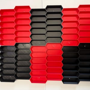 May include: A modular wall-mounted storage system featuring a grid of interlocking hexagonal compartments. The unit is composed of alternating red and black plastic sections, creating a geometric pattern with open-front bins for organization.