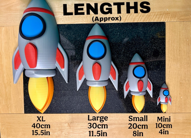 Puede incluir: Se muestran cuatro cohetes de juguete de diferentes tama&ntilde;os, de mini a XL. Los cohetes son grises con detalles en rojo y azul, y llamas amarillas y naranjas. El cohete XL mide 40 cm de alto, el grande 30 cm, el peque&ntilde;o 20 cm y el mini 10 cm.