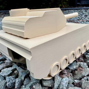 May include: A beige 3D printed model of a tank featuring a turret, a long barrel, and a series of circular wheels along the side. The tank has a matte finish with visible horizontal layer lines from the printing process and a geometric structure.