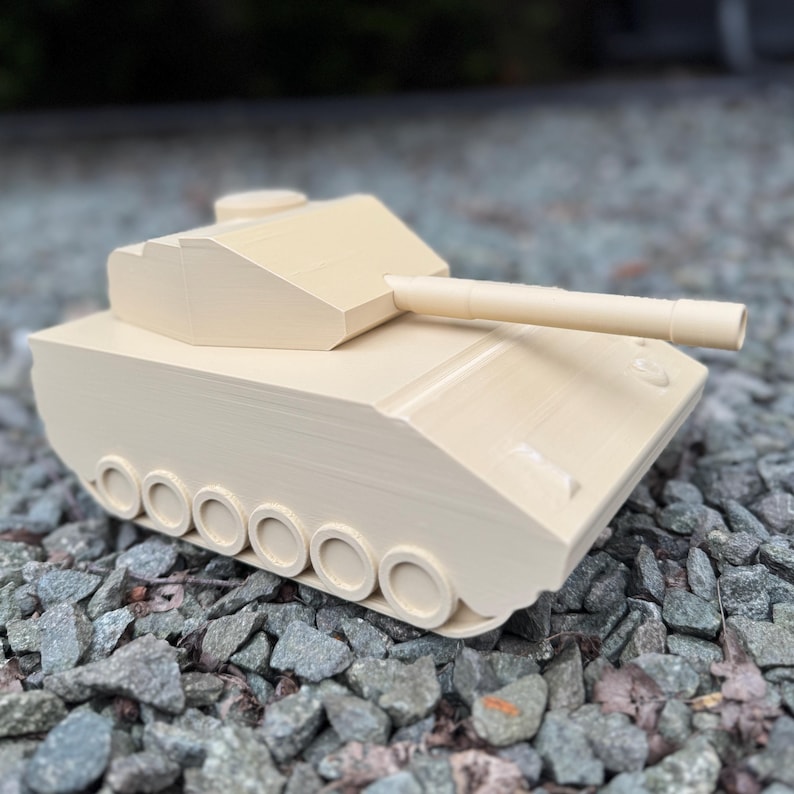May include: A beige tank model featuring a turret, a long barrel, and a series of circular wheels along the side. The structure has a smooth, matte finish with visible layered lines consistent with 3D printing, showcasing a simplified design.