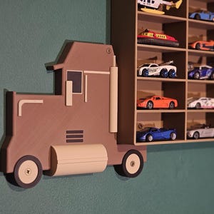 3D-printed truck-themed wall shelf with wooden finish PLA, designed for car storage. Ideal for adult and child car collectors to organise and display collectables neatly in 24 compartments. A functional decor piece that adds charm to any room.