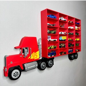 May include: A red truck-shaped wall shelf with multiple compartments, each holding a miniature toy car. The truck features a red cab with the number 95 and a trailer with several shelves. The text "Example of full truck setup" and "Link to full truck in description" are visible.