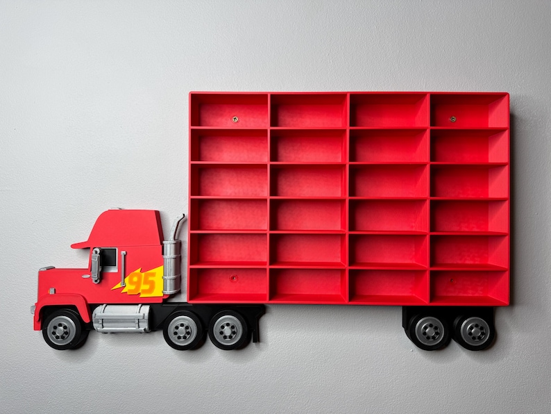 May include: A red truck-shaped wall shelf with multiple compartments. The truck cab features a yellow '95' graphic with a flame design. The shelf is mounted on a light gray wall, offering a playful storage solution.