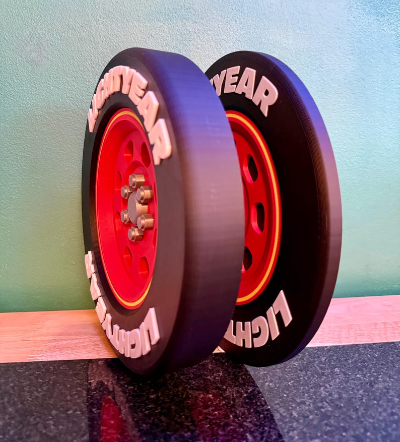 May include: Two black tires with red rims and the word "LIGHTYEAR" in white lettering. The tires are leaning against a wall. The tires have a yellow stripe around the red rim.