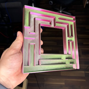 A 3D-printed, decorative light switch cover with a maze-like design. The intricate pattern adds a unique and playful touch to any room, making it both functional and visually appealing for various settings.