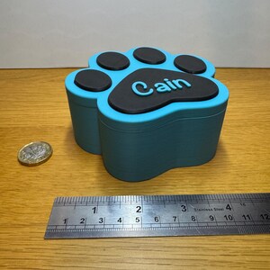 Small personalised paw print memorial box in blue and black, designed for storing pet ashes or keepsakes. Holds approx. 170ml, ideal for small pets like cats, rabbits, or toy breed dogs. Magnetic lid secures contents. Handmade Pet loss gift or urn.