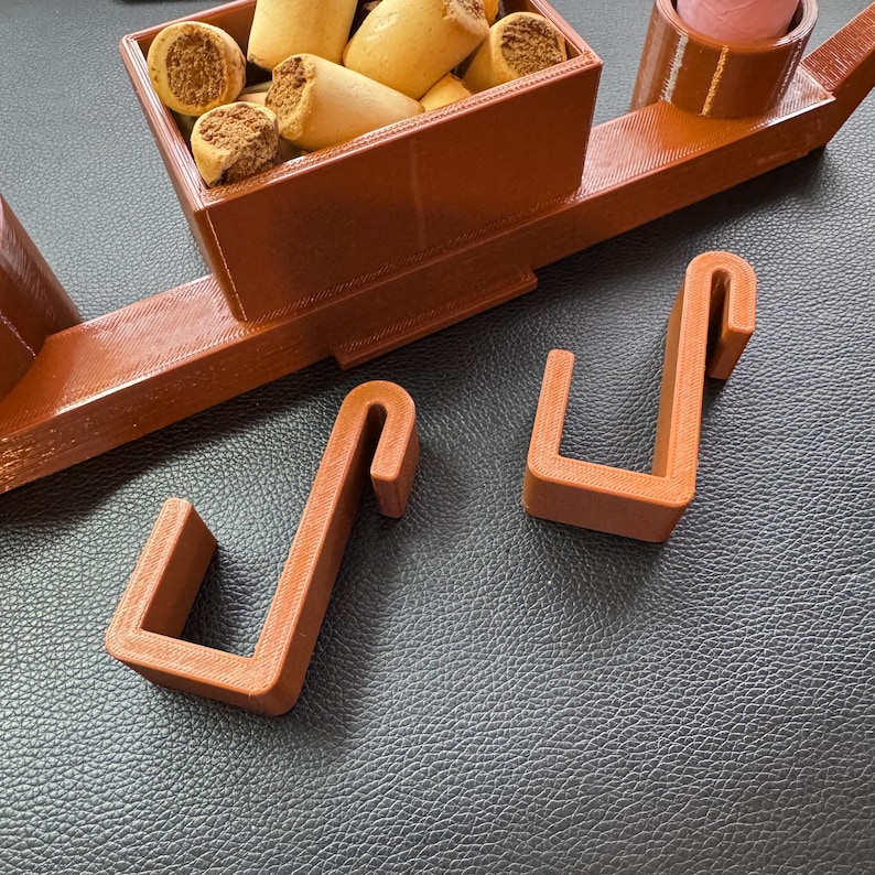 Adjustable hooks for dog crate organiser in oak wood effect. Designed to securely attach the organiser to crate gaps without tools. Ideal for holding leads, poo bags, treats, and tennis balls. Perfect for dog walkers and pet owners on the go.