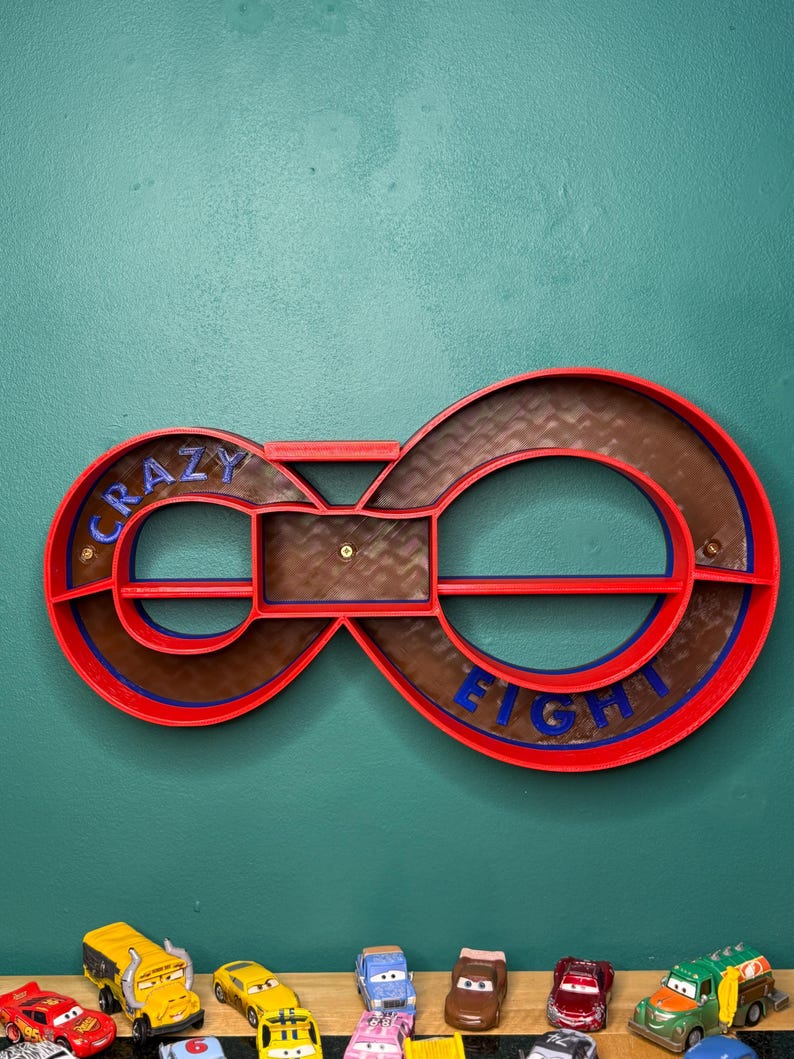 May include: A red and brown infinity-shaped shelf with the words "CRAZY EIGHT" in blue. The shelf is mounted on a teal wall. Several toy cars are lined up below the shelf.