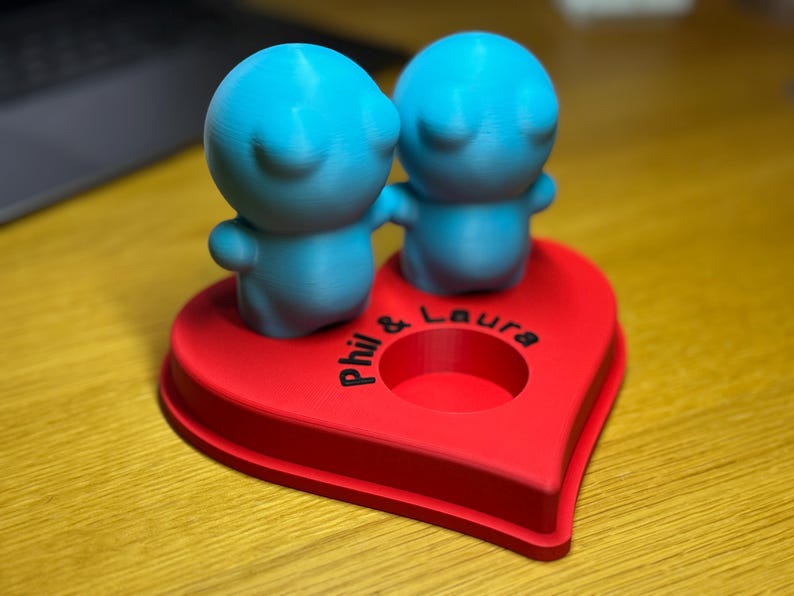 Personalised 3D printed tealight holder featuring cute bubble people figurines on a heart-shaped base. Customisable with names, perfect as a romantic Valentine’s gift, anniversary present, or home decor. Designed for use with LED tealights.