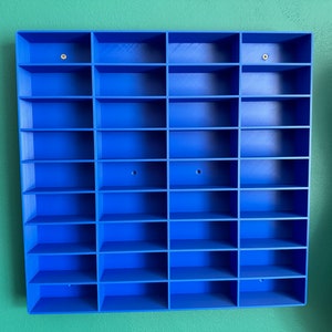 3D-printed blue shelving unit for wall-mounting, featuring multiple compartments perfect for displaying toy cars, mini figures, or small collectibles. Sleek and simple design to help organise and showcase your collection."