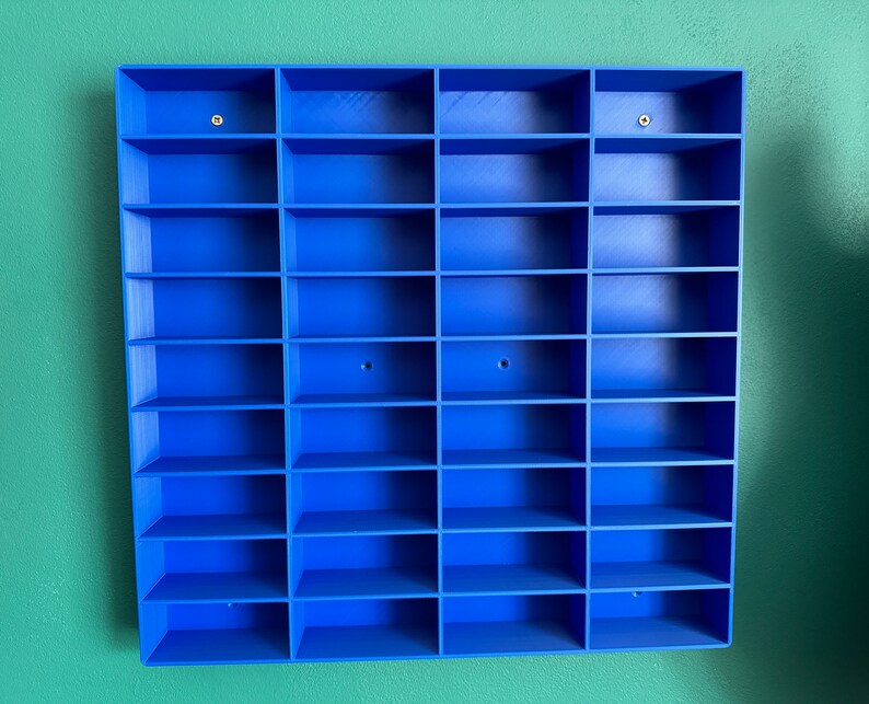 3D-printed blue shelving unit for wall-mounting, featuring multiple compartments perfect for displaying toy cars, mini figures, or small collectibles. Sleek and simple design to help organise and showcase your collection."