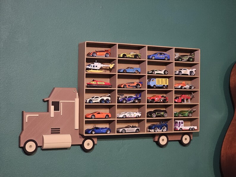3D-printed truck-themed wall shelf with wooden finish PLA, designed for car storage. Ideal for adult and child car collectors to organise and display collectables neatly in 24 compartments. A functional decor piece that adds charm to any room.