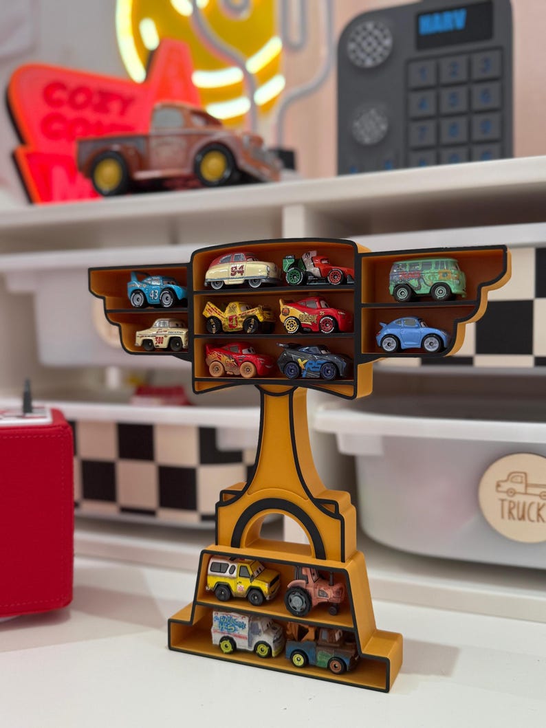 Puede incluir: Una estanter&iacute;a amarilla con forma de trofeo, llena de coches de juguete en miniatura de varios colores. La estanter&iacute;a tiene varios niveles para guardar los coches, y el dise&ntilde;o general recuerda el tema de las carreras.