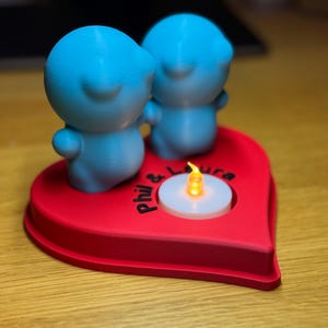 Personalised 3D printed tealight holder featuring cute bubble people figurines on a heart-shaped base. Customisable with names, perfect as a romantic Valentine’s gift, anniversary present, or home decor. Designed for use with LED tealights.