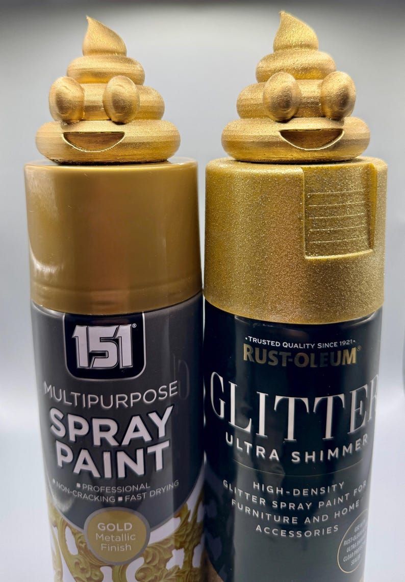 Two gold glittery 3D-printed poop emoji figurines sitting on top of gold spray paint and spray glitter cans. The cans show the paints used to achieve the metallic finish. Fun and eco-friendly decor made from recycled plastic.