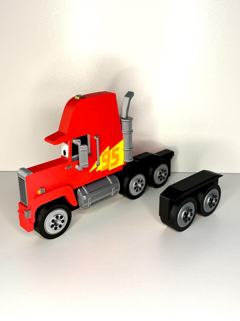 May include: A red toy truck with the number "95" in yellow lightning bolts on the side. The truck has a silver grill, exhaust pipe, and fuel tanks. The black trailer is detached.