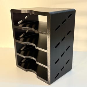 May include: A black wooden wine rack with a rectangular shape. The rack has multiple shelves with curved edges to hold wine bottles. The sides of the rack have a series of angled cutouts. The edges of the rack have a silver finish.