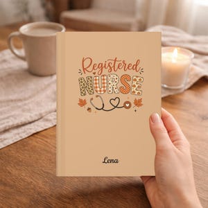 May include: A tan notebook featuring the text Registered NURSE in a decorative font with patterns including leopard print, plaid, and pumpkins. Below the text is a stethoscope illustration, autumn leaves, and the name Lena printed in black.