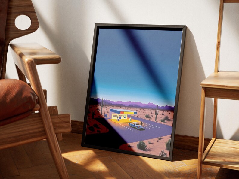 May include: A framed print of a desert landscape with a yellow and blue building and a car driving away. The sky is a gradient of blue and purple.
