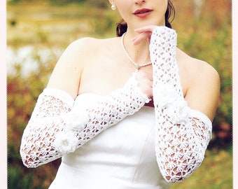 May include: A bride wearing a white wedding dress with crocheted lace sleeves. She is wearing a pearl necklace and earrings.