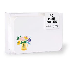 Könnte beinhalten: Ein Set aus 40 Mini-Notizzetteln in einer durchsichtigen Kunststoffbox. Die weißen Karten zeigen eine kleine Illustration eines gelben Kruges mit rosa, gelben und violetten Blumen. Ein weißes Etikett auf der Box trägt die Aufschrift 40 MINI NOTES und smile every day.