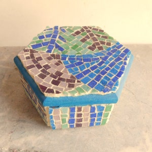May include: A hexagonal mosaic box with a blue, green, and purple design. The box is made of small tiles and has a blue border.