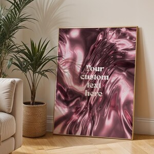 Peut inclure: Intérieur de salon avec un canapé beige, des coussins et une couverture. Une œuvre d'art encadrée avec un design abstrait rose et le texte "Your custom text here" est appuyée contre le mur. Des plantes en pot ajoutent de la verdure.