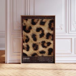 May include: A framed print displaying a close-up of leopard fur in brown and black tones. The print includes the word "LEOPARD" and the scientific name "Panthera pardus". Text below describes the leopard's symbolism: strength, courage, stealth, patience, self-reliance, and adaptability.
