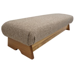 May include: A brown upholstered footstool with a wooden base. The footstool has a curved top and a simple design.