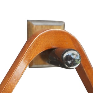 Puede incluir: Un estante de billar triangular de madera con una punta de goma negra. El estante está hecho de madera oscura y tiene un acabado liso.