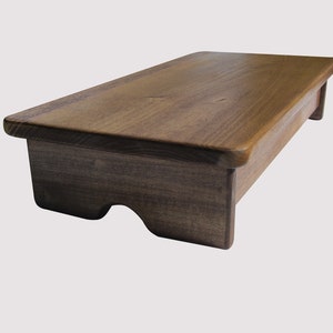 May include: A dark brown wooden step stool with rounded edges. The stool is made of solid wood and has a simple, classic design.