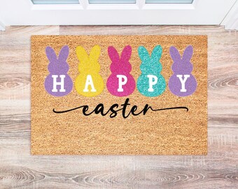 May include: A brown coir doormat with the words "Happy Easter" in white letters and five pastel-colored bunny shapes spelling out the word "HAPPY".