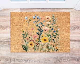 May include: A doormat with a floral design featuring yellow, blue, and pink flowers on a brown background.