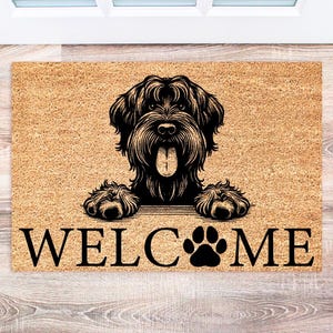 May include: A rectangular doormat with a black dog illustration and the word "WELCOME". The dog has its tongue out and paws visible. The mat is made of a light brown material.