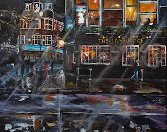 May include: An oil painting depicts a nighttime street scene with a pub called "The Cambridge." The building has lit windows, reflecting warm light onto the wet street. A person walks on the sidewalk. The artwork has a dark, moody atmosphere.