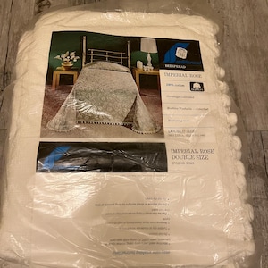 May include: A packaged Imperial Rose double-size bedspread. The packaging includes a picture of the bedspread on a bed, with a floral design. The label indicates it is 100% cotton and machine washable.