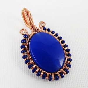 Pode incluir: Um pingente envolto em fio de cobre com uma pedra oval azul escura e contas azuis escuras.