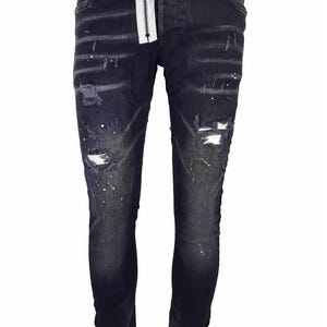 Peut inclure: Jean en denim délavé foncé avec des détails usés, notamment des déchirures et des éclaboussures de peinture blanche. Fermeture éclair blanche et fermeture boutonnée. Coupe slim et design classique à cinq poches.