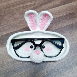 May include: White crocheted glasses holder shaped like a bunny with pink ears and black glasses inside.